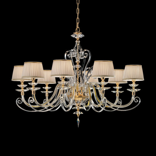 Classic Style Chandelier With Swarovski® Crystals The Classic Style Chandelier With Swarovski® Crystals is an elegant, multi-arm fixture adorned with golden and clear Swarovski® crystal components. It features ten beige pleated lampshades and hangs from a gold chain, set against a black background. The intricate detailing enhances its luxurious appearance.