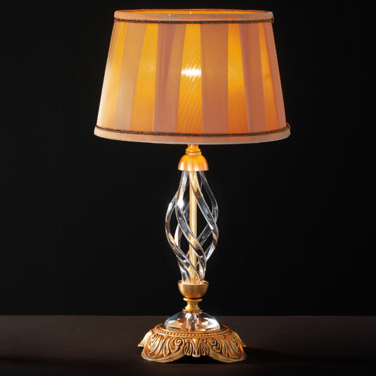The Classic Style Twisted Table Lamp, boasting a gold and crystal base with intricate detailing, stands on a dark surface. Its soft, translucent amber lampshade with vertical stripes casts a warm glow, infusing the room with timeless elegance.