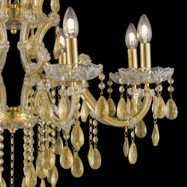 Gold Leaf Glass Chandelier An up-close shot of the Gold Leaf Glass Chandelier reveals its golden accents and clear, teardrop-shaped crystals adorning the arms. The chandelier's lit candle-like bulbs illuminate the individual beads and crystals, reflecting light to create a luxurious and elegant ambiance.