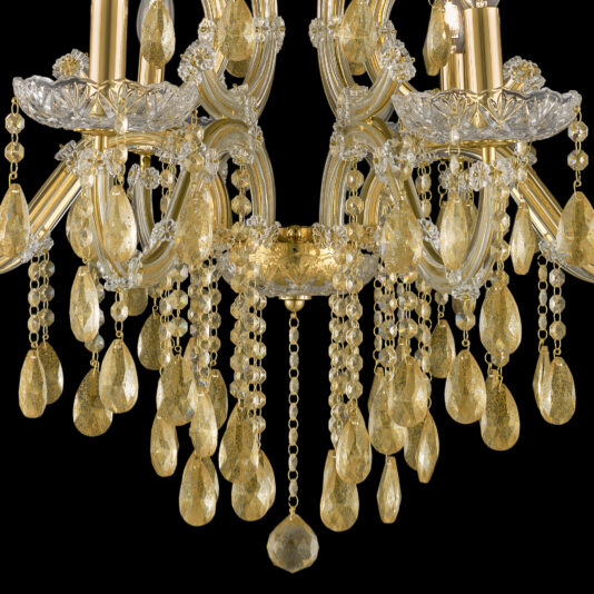 Gold Leaf Glass Chandelier A detailed close-up of the Gold Leaf Glass Chandelier showcases its ornate design, with numerous golden teardrop crystals and intricate gold detailing. Against a black background, the chandelier radiates an opulent and luxurious appearance.