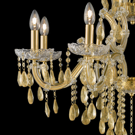 Gold Leaf Glass Chandelier The Gold Leaf Glass Chandelier is an elaborate fixture featuring multiple lit candle-shaped bulbs. It boasts intricate gold detailing, hanging crystal glass ornaments, and teardrop-shaped embellishments set against a black background.