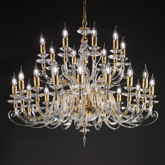 A majestic Large Classic Candle Style Chandelier hangs from the ceiling against a dark background. It features multiple tiers of gold and transparent, intricately curved arms adorned with candle-like light fixtures, emitting a bright, sparkling glow.