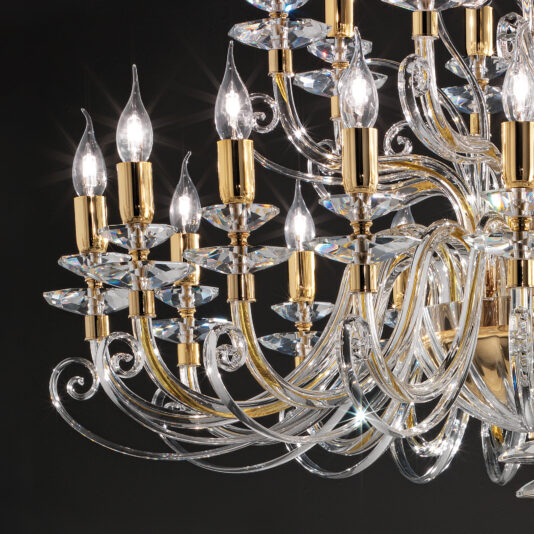 Large Classic Candle Style Chandelier The Large Classic Candle Style Chandelier exudes luxury with its grand size and stunning design. It features multiple candle-like light bulbs elegantly mounted on gold fixtures. The intricate piece showcases swirling glass arms and sparkling crystal accents that create a beautiful prismatic effect against a dark background.