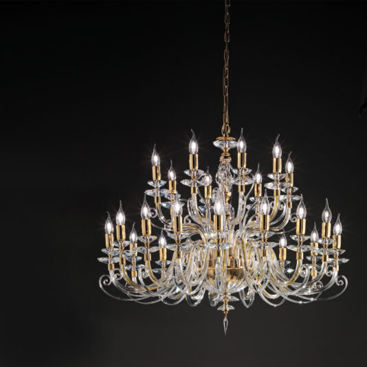 Large Classic Candle Style Chandelier The Large Classic Candle Style Chandelier is an ornate, multi-tiered crystal chandelier adorned with numerous candle-shaped light bulbs set against a black background. It boasts a detailed, elegant design with gold accents and intricate glasswork, embodying timeless sophistication.