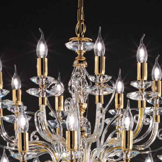 Large Classic Candle Style Chandelier A close-up view of the Large Classic Candle Style Chandelier reveals its numerous candle-like bulbs, adorned with gold accents and intricate glass detailing. The illuminated bulbs emit a luxurious and elegant glow against a dark background.
