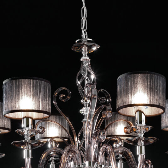 A close-up of the Modern Smoked Glass Chandelier, capturing its elegant and modern design. The intricate glasswork and multiple light bulbs are highlighted, featuring ornate swirls and fabric lampshades that emit a soft glow against a dark background.
