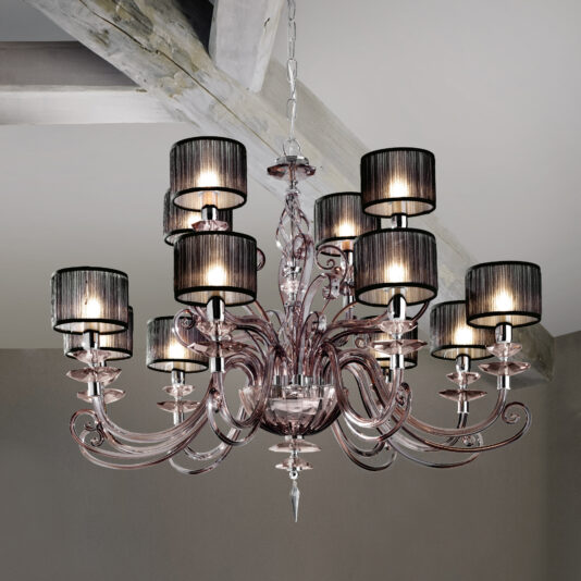 The Modern Smoked Glass Chandelier With Shades features intricate designs and nine black fabric lampshades, hanging from the ceiling and emitting a warm glow. It is beautifully set against a neutral-colored wall and wooden ceiling beams.