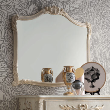 Classic Rococo Style Overmantel Mirror A vintage, ornate Classic Rococo Style Overmantel Mirror with a cream-colored frame hangs on a wall adorned with leafy black-and-white wallpaper. Below, a dresser showcases decorative items such as a round abstract art piece, ceramic vases, and a silver figurine.