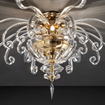 Contemporary Glass Swirl Ceiling Light The Contemporary Glass Swirl Ceiling Light is a luxurious fixture featuring ornate, curling glass arms radiating from a central golden point. This modern piece showcases intricate detailing and includes a large central glass section that elegantly tapers into a pointed crystal drop, all set against a dark background.