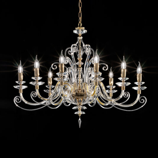 An Oval Candle Style Chandelier with luxurious design features twelve candle-shaped light bulbs arranged in two tiers, intricate gold detailing, and crystal adornments. The chandelier hangs gracefully against a black background, showcasing its elegant and sophisticated design with curling arms and pendant crystals.