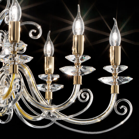 A close-up of the Oval Candle Style Chandelier features four illuminated candle-like bulbs. Each bulb is supported by intricately twisted, gold-colored arms adorned with crystal accents. The black background enhances the brightness and sparkle of the chandelier's crystals.