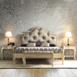 A luxurious bedroom showcases the Romantic Button Upholstered Bed, complete with an ornate tufted headboard and patterned bedding. Two side tables, each holding a lamp that casts a warm glow, flank the bed. The wallpaper behind features a detailed, nature-inspired design.