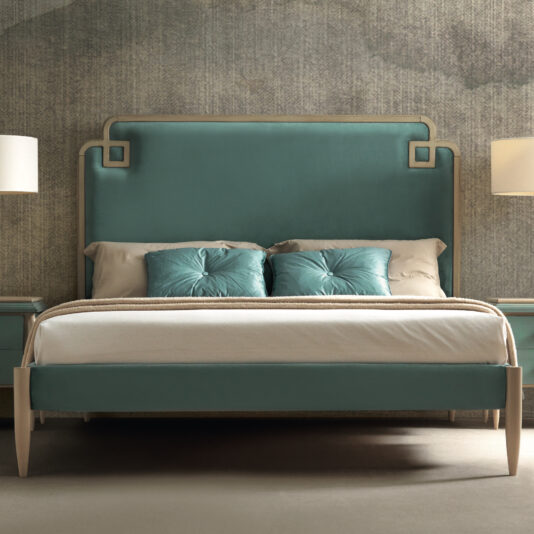 A modern bedroom showcases the Luxury Art Deco Style Bed, featuring a teal upholstered headboard and matching teal cushions. The neutral bedding is complemented by two bedside tables with white lamps, all set against a textured grey wall. The decor is minimalistic, exuding a sophisticated Art Deco style.