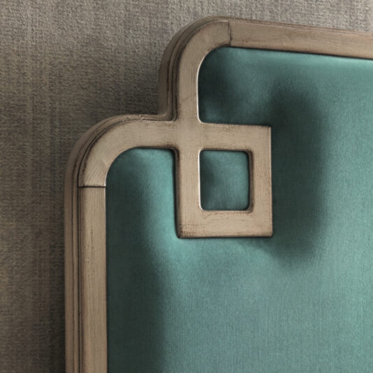 Luxury Art Deco Style Bed Close-up of the Luxury Art Deco Style Bed's headboard showcasing its geometric design. This exquisite bed features a wooden frame with a pale finish, highlighted by an upholstered panel in teal fabric. The design is distinguished by sharp corners and a small square cutout detail at the top left corner.