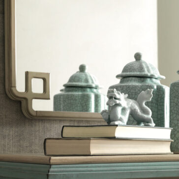 Luxury Square Art Deco Style Mirror A decorative vanity featuring the Luxury Square Art Deco Style Mirror with a unique corner cutout design. In front, three green, cracked ceramic containers are placed. Two stacked books with a small, artistic sculpture of a mythical creature rest atop the books, adding an Art Deco style touch.