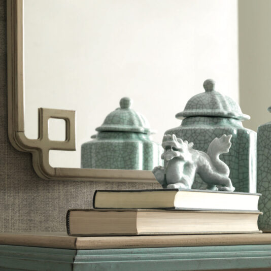 Luxury Square Art Deco Style Mirror A decorative vanity featuring the Luxury Square Art Deco Style Mirror with a unique corner cutout design. In front, three green, cracked ceramic containers are placed. Two stacked books with a small, artistic sculpture of a mythical creature rest atop the books, adding an Art Deco style touch.