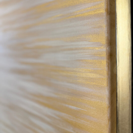 Pair Of Original Abstract Paintings Close-up of the Original Gold Leaf Abstract Painting (Copy) showcasing horizontal streaks of gold and beige tones. The texture appears smooth with shimmering gold accents. The image captures the corner of the canvas along with a thin, golden frame edge.