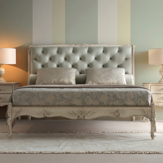 A luxurious bedroom showcases a Classic Louis Style Button Upholstered Bed, complete with a button-tufted headboard and elegant patterned bedding. The room is complemented by two matching nightstands, each adorned with a lamp, and softly striped walls in pastel shades.