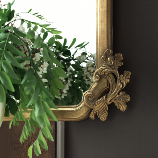 Large Rococo Style Overmantle Mirror The Large Rococo Style Overmantle Mirror showcases an ornate gold frame adorned with a decorative leaf design at the corners. It beautifully reflects green plants with delicate white flowers against a dark background, highlighting the striking contrast between the vibrant foliage and the frame's elegance.
