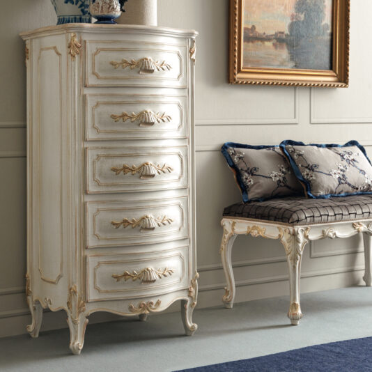 A vintage-style room featuring the Ornate Classic Style Tallboy with gold accents beside a cushioned bench adorned with decorative pillows. A framed painting hangs gracefully above the bench, completing the look. The walls are painted in a light neutral color.