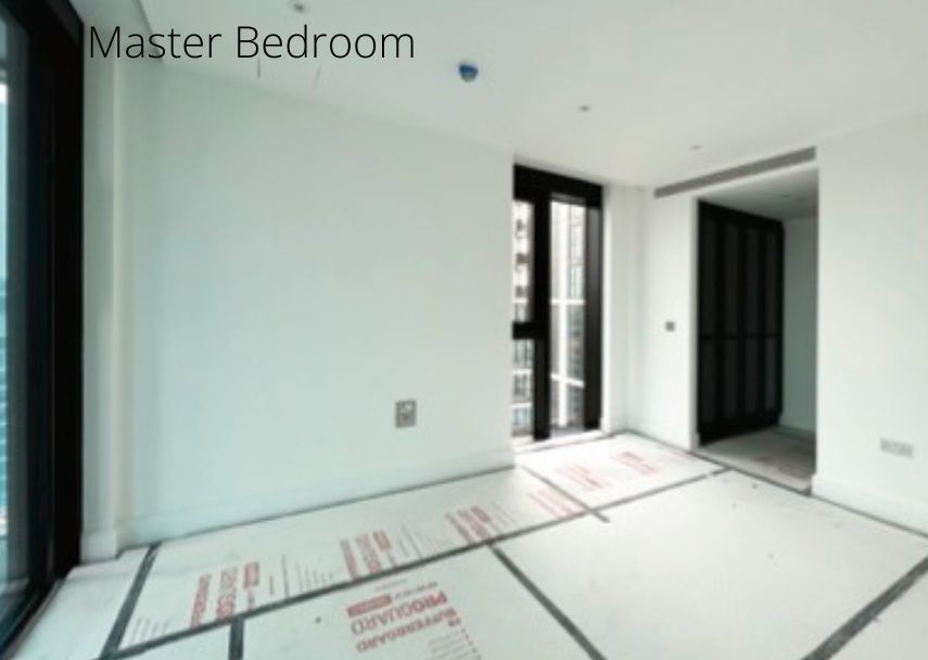 An empty master bedroom with large windows, covered floor, and white walls. The room is bright with sunlight streaming in through the black-framed sliding doors leading to a separate area, showcasing design worthy of a UK Property Award.