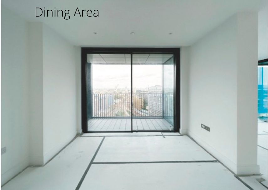 An award-winning dining area with white walls features a large sliding glass door leading to a balcony. The unfurnished, uncarpeted room offers a breathtaking view of the city skyline. Text on the wall reads "Dining Area," embodying the elegance deserving of a UK Property Award.