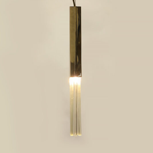 The Glass Drop Pendant Light features a contemporary design with a sleek gold cylindrical cover and transparent tubular extensions, casting a warm glow against a neutral beige background.