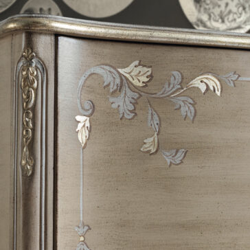 High End Rococo Inspired Cabinet Close-up of a High End Rococo Inspired Cabinet corner showcasing intricate carved floral motifs and sophisticated detailing. The wood features a vintage finish, enhanced by subtle metallic accents on the floral patterns.