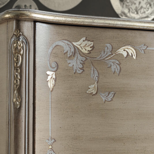 High End Rococo Inspired Cabinet Close-up of a High End Rococo Inspired Cabinet corner showcasing intricate carved floral motifs and sophisticated detailing. The wood features a vintage finish, enhanced by subtle metallic accents on the floral patterns.