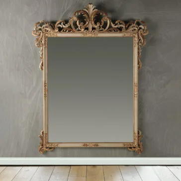 Large Baroque Style Wall Mirror The Large Baroque Style Wall Mirror, distinguished by its intricate, decorative frame with elaborate scrollwork and floral designs, is mounted on a textured gray wall. Part of a wooden floor can be seen at the bottom.