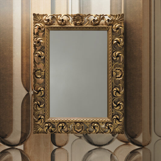 The Ornate Baroque Style Wall Mirror, showcasing its intricate floral and scroll designs, hangs empty on a patterned wall. The mirror's gold frame contributes an elegant touch to the setting.