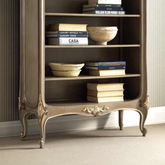 Rococo Inspired Bookcase The Rococo Inspired Bookcase, featuring ornate legs, elegantly displays a collection of books and decorative bowls. Titles such as