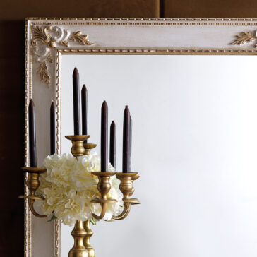 Rococo Style Rectangular Wall Mirror A Rococo Style Rectangular Wall Mirror with an ornate and detailed frame enhances the elegance of the arrangement, featuring a decorative candelabra adorned with dark candles and white flowers.