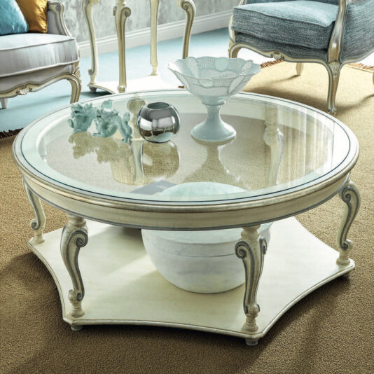 Rococo Style Round Glass Coffee Table The Rococo Style Round Glass Coffee Table enhances the room with its intricate legs, adorned on top with decorative pieces such as a ceramic bowl, black vase, and figurine. On the lower shelf, a striking marble ball catches the eye. This sophisticated arrangement is finished off with stylish chairs and a plush carpet.