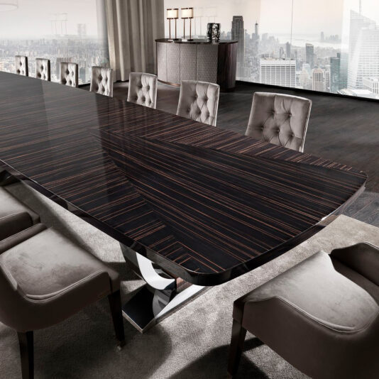 A sleek, modern conference room showcases a stunning Large Italian Dining Table with a dark, polished finish, complemented by plush, beige upholstered chairs. Expansive windows reveal a city skyline in the background, infusing natural light into this elegant setting.