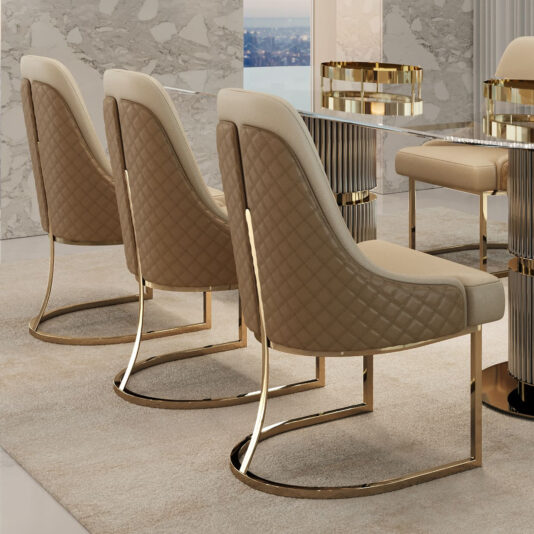 Three elegant chairs with quilted beige upholstery and gold metal frames are arranged beside a Contemporary Oval Glass Dining Set in a luxurious dining area, featuring marble accents and a large window view.