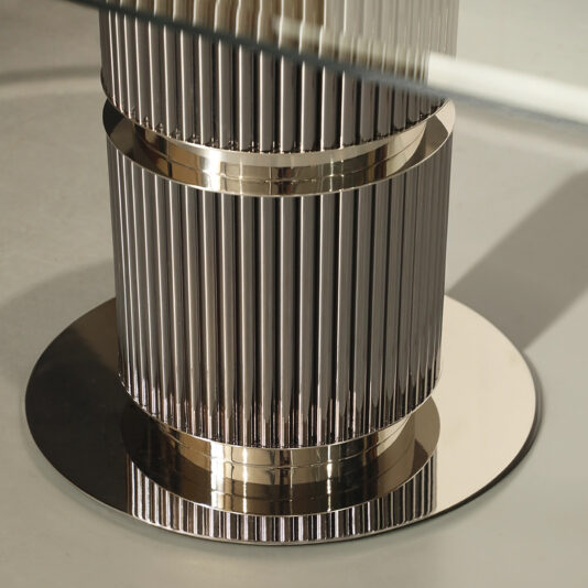 Close-up of a sleek, metallic ribbed cylindrical structure on a round base resembling the Contemporary Oval Glass Dining Table, with its reflective surface capturing light and a glass piece visible at the top edge.