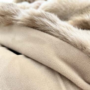 Beige Textured Faux Fur Throw Close-up of the Beige Textured Faux Fur Throw highlights its soft texture and fluffy fur trim, exuding plushness and warmth for ultimate comfort.
