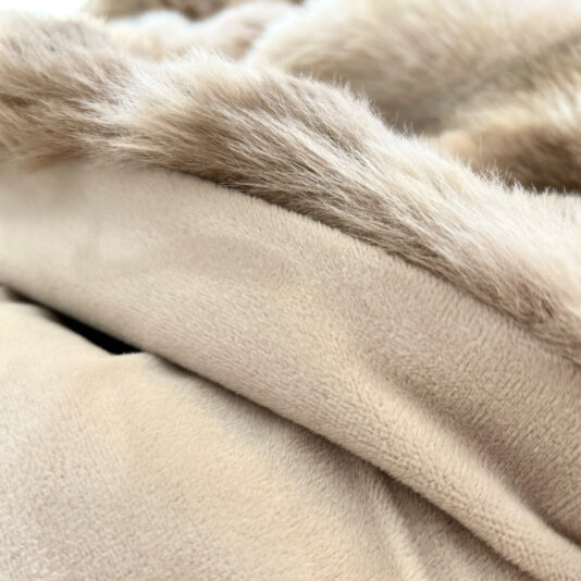Close-up of the Beige Textured Faux Fur Throw highlights its soft texture and fluffy fur trim, exuding plushness and warmth for ultimate comfort.