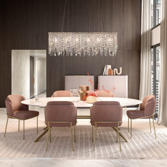 Contemporary Rectangular Cut Crystal Chandelier A stylish dining room features a white oval table, six plush pink chairs on a striped rug, and the Contemporary Rectangular Cut Crystal Chandelier above. Soft, neutral walls and cabinets are accented by red floral decor, while large windows flood the space with natural light.