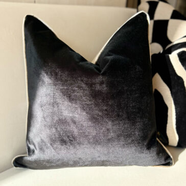 Luxury Velvet Double Sided Scatter Cushion A Luxury Velvet Double Sided Scatter Cushion with a subtle sheen is on a light-colored couch, with a patterned black and white pillow behind it for contrast.