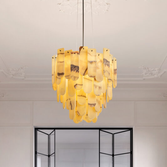 The Modern Onyx Oval Chandelier showcases layered amber glass pieces that cast a warm glow, elegantly hanging from a white ceiling with decorative molding to illuminate a room with white walls and glass-paneled doors.