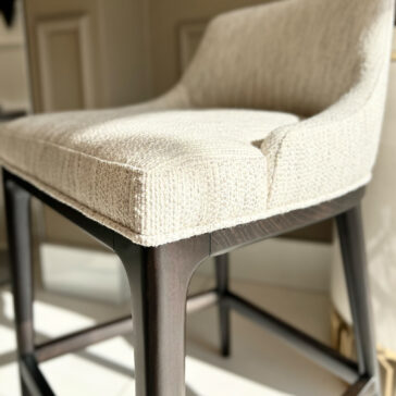 A beige upholstered chair with textured fabric and dark wooden legs enhances a well-lit room, pairing perfectly with the 