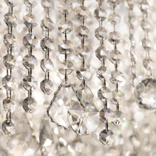 Close-up of sparkling beads from the Oval Cut Crystal Pendant Chandelier, with varied shapes catching and refracting light to create a shimmering display. The blurred background enhances the glistening crystal details.