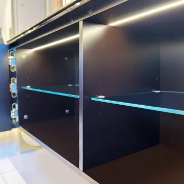 Luxury Art Deco Style Sunburst Sideboard The Luxury Art Deco Style Sunburst Sideboard is shown with its door open, revealing a dark wood interior, glass shelves, metal hinges, and built-in LED strip lighting that highlights its modern and clean design.