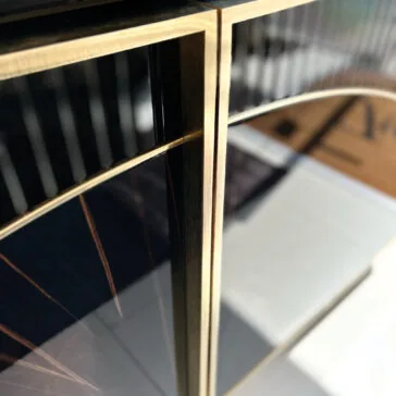 Luxury Art Deco Style Sunburst Sideboard Close-up of the Luxury Art Deco Style Sunburst Sideboard in black and gold, showcasing reflective surfaces, sharp lines, and a modern sunburst design with sunlight casting dramatic shadows.