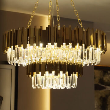 Modern Tiered Crystal Chandelier The Modern Tiered Crystal Chandelier boasts two tiers of smoked cut crystals and gold accents, casting a warm, elegant glow. It is suspended by gold chains from the ceiling, enhancing any room with sophistication.