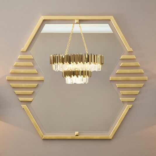 Modern Tiered Crystal Chandelier A hexagonal mirror with a gold frame reflects the Modern Smoked Cut Crystal Chandelier, featuring tiers of crystal-like elements. The mirror also has horizontal gold accents on its sides.