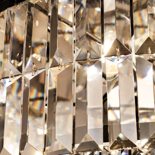The Modern Smoked Cut Crystal Chandelier features rectangular, faceted prisms in vertical rows that reflect and refract light, creating a sparkling colorful effect. The well-polished prisms enhance its elegant look.