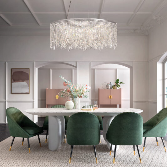 Oval Cut Crystal Pendant Chandelier A modern dining room showcases a large oval table with six green chairs. Above, a Round Cut Crystal Pendant Ceiling Light casts a warm glow on the floral centerpiece. The white walls are adorned with tall cabinets and framed art.